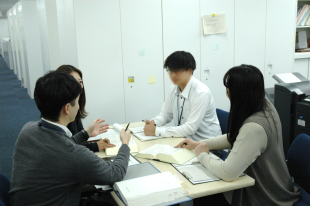 S係長と２人の係員とでミーティングをする様子